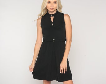 May include: A black sleeveless dress with a mock neck and a small keyhole detail at the neckline. The dress has a fitted bodice and a slightly flared skirt.