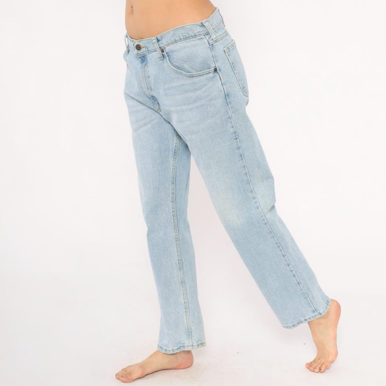 May include: Light blue denim jeans with a classic five-pocket design. The jeans have a straight leg cut and a faded wash, creating a vintage look. The jeans are made of a durable denim material.