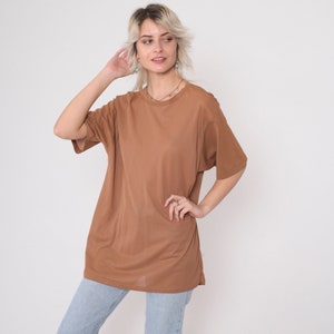 May include: An oversized brown t-shirt with short sleeves and a crew neck.