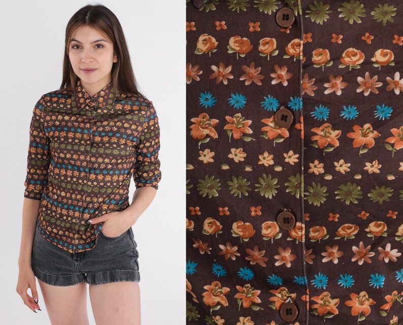 May include: A brown button-up shirt with a floral pattern in shades of orange, blue, and green. The shirt has a collar and long sleeves.