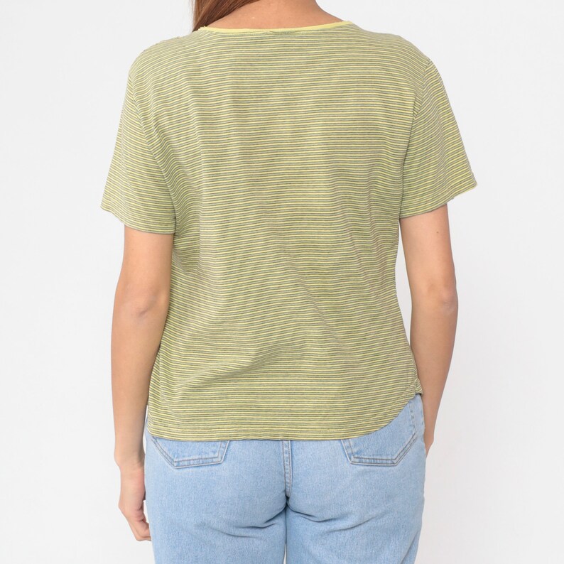 Peut inclure: T-shirt &agrave; manches courtes &agrave; rayures vertes claires et jaunes. Le col est rond et le t-shirt est port&eacute; avec un jean bleu clair. Le mod&egrave;le est vu de dos.