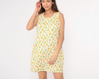 May include: A sleeveless white dress with a floral print featuring yellow and green flowers.