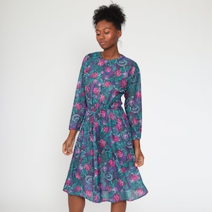May include: A teal blue midi dress with a floral print featuring pink and purple flowers. The dress has a button-up front and a cinched waist.