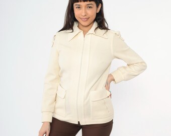May include: A cream-colored zip-up jacket with a collar and two pockets. The jacket has a slightly textured fabric.