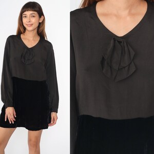 May include: A black velvet skirt with a black satin top featuring a bow detail. The top has long sleeves and a v-neck.