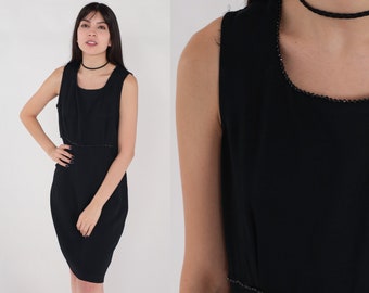 May include: A sleeveless black dress with a square neckline and a fitted silhouette. The dress is adorned with a delicate beaded trim along the neckline and waist. A black choker necklace completes the look.