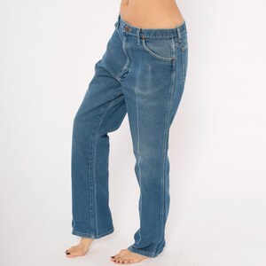 Peut inclure: Jean en denim bleu avec une coupe droite classique. Le jean a une fermeture boutonn&eacute;e et zipp&eacute;e, avec des poches avant et arri&egrave;re. Le denim a un d&eacute;lavage, lui donnant un aspect vintage. Le jean est bleu moyen.