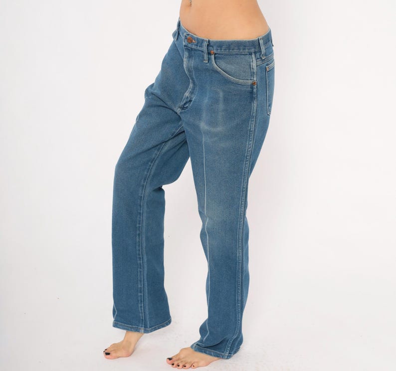 Peut inclure: Jean en denim bleu avec une coupe droite classique. Le jean a une fermeture boutonn&eacute;e et zipp&eacute;e, avec des poches avant et arri&egrave;re. Le denim a un d&eacute;lavage, lui donnant un aspect vintage. Le jean est bleu moyen.