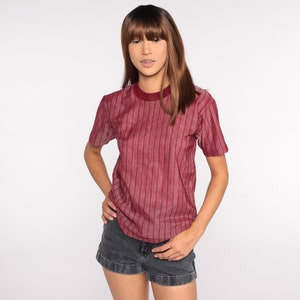 May include: A maroon striped short-sleeved shirt with a crew neck.