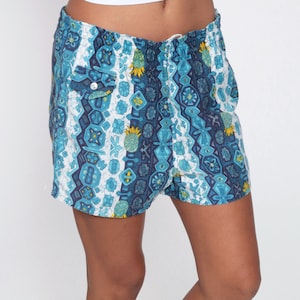 May include: Blue and white patterned shorts with a geometric design. The shorts have a drawstring waist and a button closure.