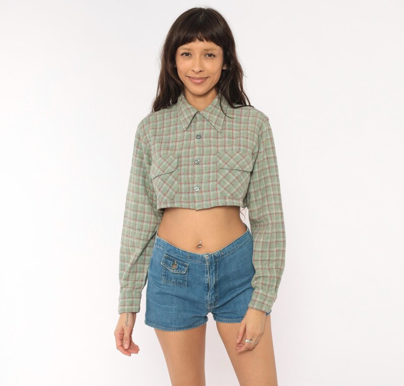 Puede incluir: Una camisa corta de manga larga con botones en un patr&oacute;n de cuadros verde salvia y rojo con dos bolsillos en el pecho, combinada con pantalones cortos de mezclilla azul con un bolsillo delantero peque&ntilde;o con bot&oacute;n y cierre de cremallera.