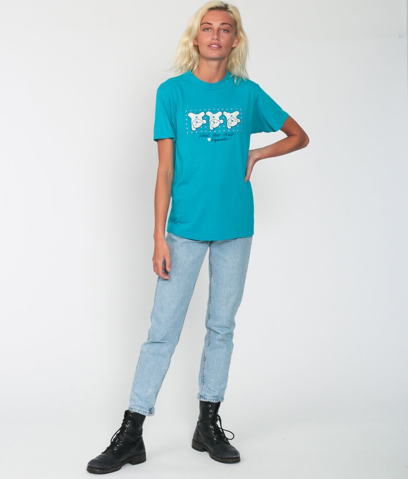 May include: A turquoise blue t-shirt with a graphic of three white cartoon bears wearing hats. The text "Love the Bears" is printed below the bears.