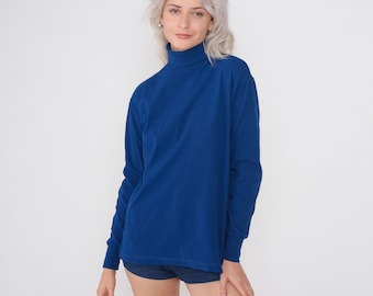 May include: A long-sleeved, blue turtleneck shirt. The shirt is made of a soft, comfortable fabric and has a relaxed fit.