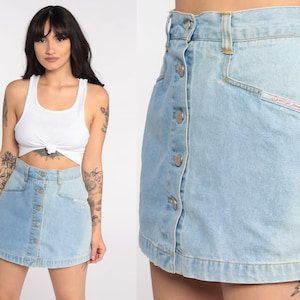 May include: A light blue denim mini skirt with a button-up front and a small embroidered logo that says "Esprit Jeans".