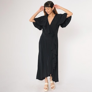 May include: A black wrap dress with a ruffled neckline and short sleeves. The dress has a flowing skirt and is cinched at the waist.