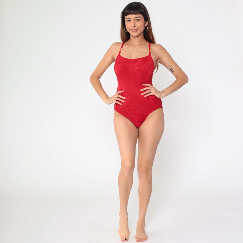 Peut inclure: Un maillot de bain rouge une pi&egrave;ce avec un motif textur&eacute;. Le maillot de bain a des bretelles fines et un d&eacute;collet&eacute; arrondi.