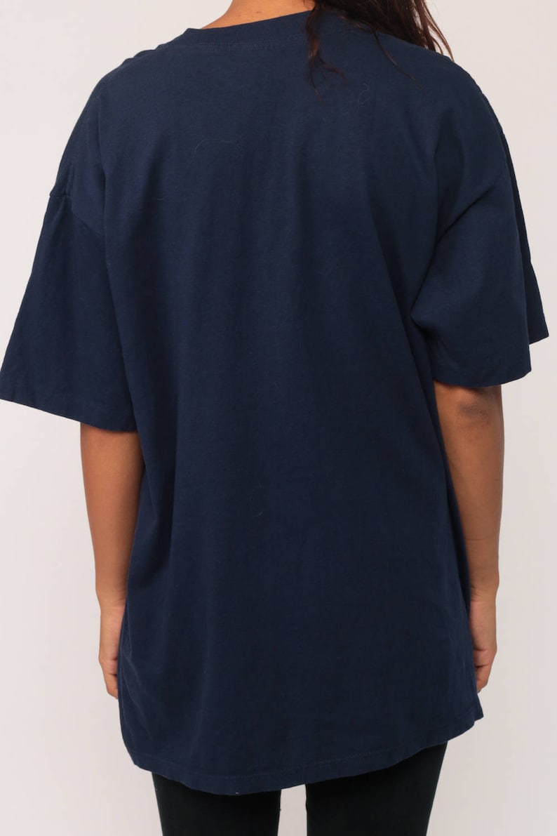May include: Navy blue t-shirt with short sleeves. The shirt has a relaxed fit and a simple, classic design. The fabric appears to be a soft, comfortable material, suitable for casual wear. The back of the shirt is visible.