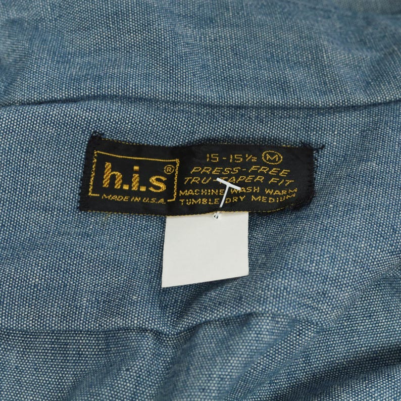 May include: A black and gold label with the text "his" and "MADE IN U.S.A."  The label also includes the text "15-15 1/2 M PRESS-FREE TRUCAPER FIT MACHINE WASH WARM TUMBLE DRY MEDIUM".