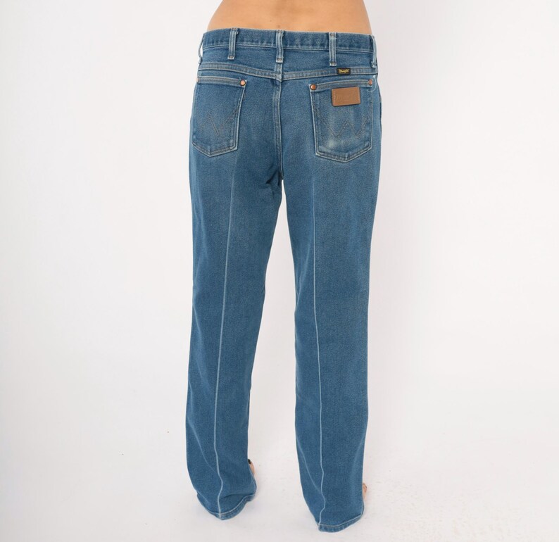 Peut inclure: Jean bleu en denim avec une conception classique &agrave; cinq poches. Le jean a une coupe droite et un patch en cuir marron au dos. Les coutures sont bleu clair, cr&eacute;ant un contraste avec le denim.