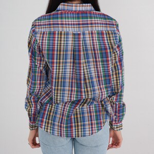 Pode incluir: Uma camisa de manga comprida com bot&otilde;es em xadrez azul, vermelho, verde e amarelo. A camisa tem um caimento solto e &eacute; feita de um tecido leve.