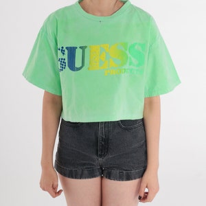May include: A green cropped t-shirt with a rainbow coloured "GUESS PRODUCTS" logo.