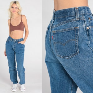 May include: A pair of blue denim jeans with a high waist and a straight leg. The jeans have a classic five-pocket design and a button fly.
