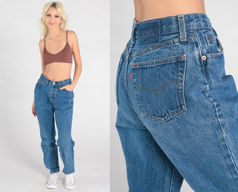 May include: A pair of blue denim jeans with a high waist and a straight leg. The jeans have a classic five-pocket design and a button fly.