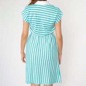 May include: A teal and white striped dress with a collared neckline and short sleeves. The dress has a fitted bodice and a slightly flared skirt.