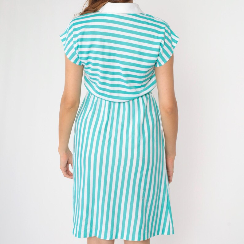 May include: A teal and white striped dress with a collared neckline and short sleeves. The dress has a fitted bodice and a slightly flared skirt.