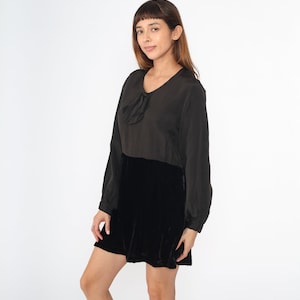 May include: A black velvet dress with a long sleeve top and a bow detail at the neckline.