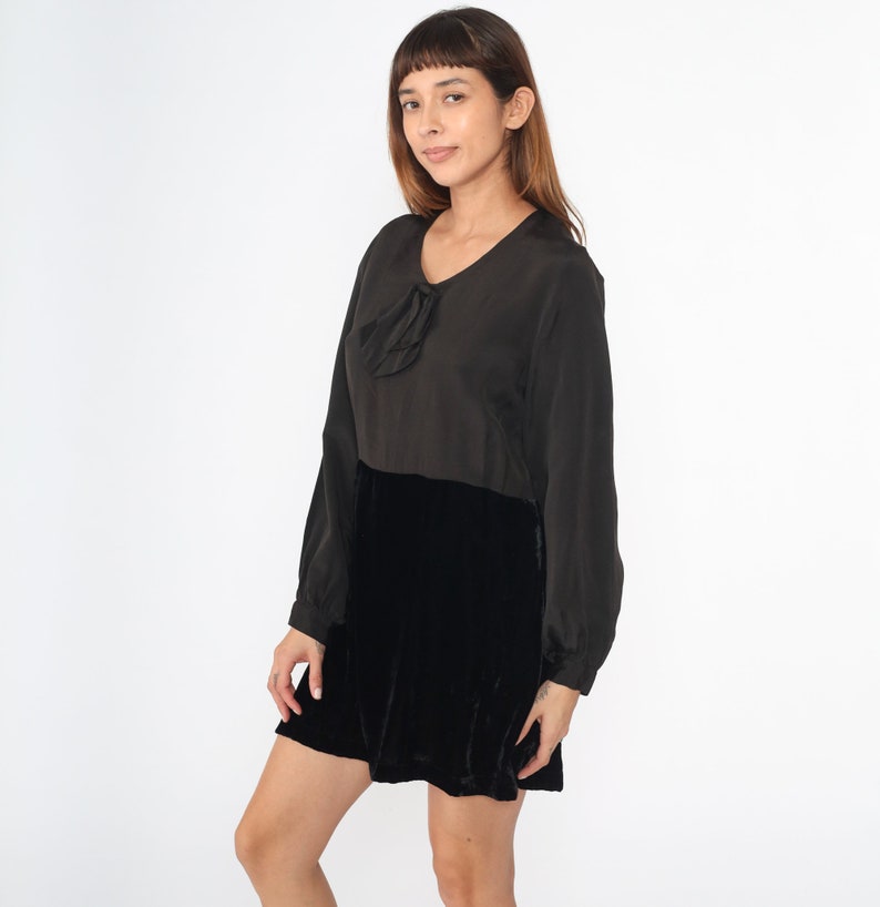 May include: A black velvet dress with a long sleeve top and a bow detail at the neckline.