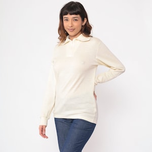 May include: A white long-sleeved collared shirt with a zipper closure.