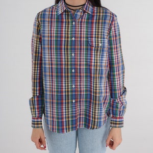 Pode incluir: Uma camisa de bot&otilde;es de manga comprida com um padr&atilde;o xadrez multicolorido. A camisa tem um padr&atilde;o xadrez azul, verde, vermelho e amarelo.