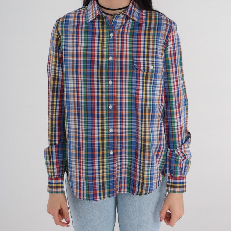 Pode incluir: Uma camisa de bot&otilde;es de manga comprida com um padr&atilde;o xadrez multicolorido. A camisa tem um padr&atilde;o xadrez azul, verde, vermelho e amarelo.