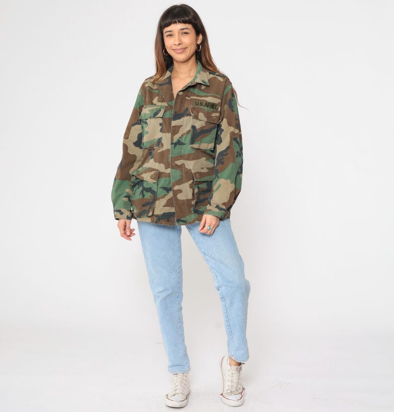 May include: A camouflage jacket with a button-up front and two large pockets. The jacket has the text "U.S. ARMY" embroidered on the left chest.