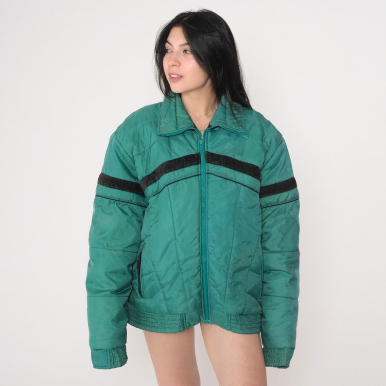 May include: A teal blue puffer jacket with black and brown stripes on the sleeves and a zipper closure.