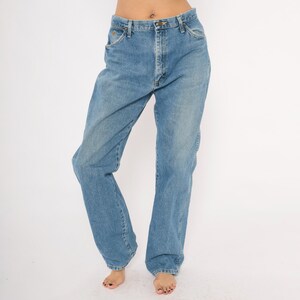 Pu&ograve; includere: Jeans di denim blu chiaro con un classico design a cinque tasche. I jeans hanno una vestibilit&agrave; a gamba dritta e una chiusura con bottoni e cerniera. Il denim ha un lavaggio sbiadito, che conferisce ai jeans un aspetto vintage. I jeans sono indossati da una persona.