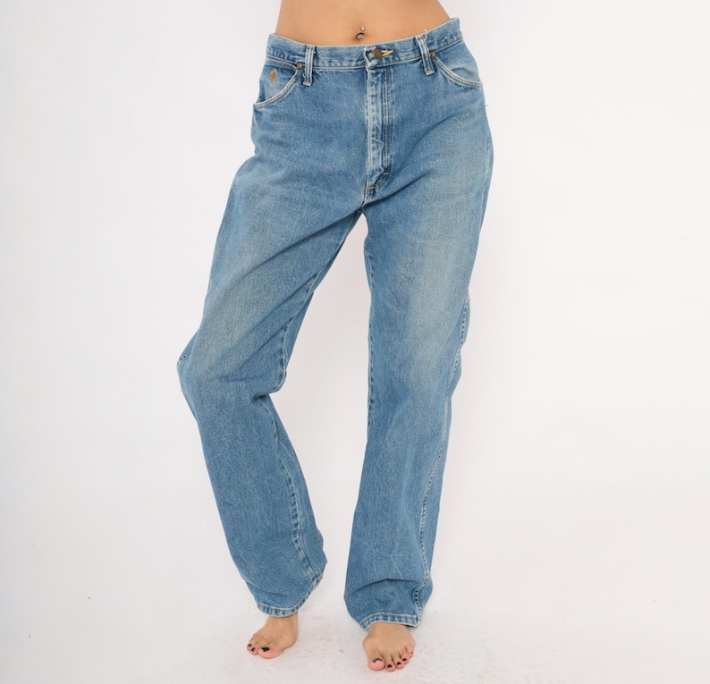 Pu&ograve; includere: Jeans di denim blu chiaro con un classico design a cinque tasche. I jeans hanno una vestibilit&agrave; a gamba dritta e una chiusura con bottoni e cerniera. Il denim ha un lavaggio sbiadito, che conferisce ai jeans un aspetto vintage. I jeans sono indossati da una persona.