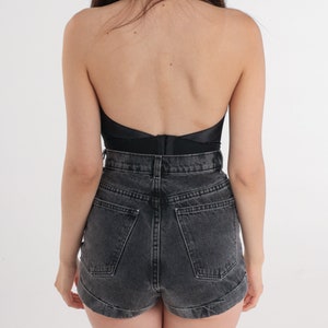 Puede incluir: Un top negro de tirantes con la espalda descubierta y unos pantalones cortos de mezclilla negros.