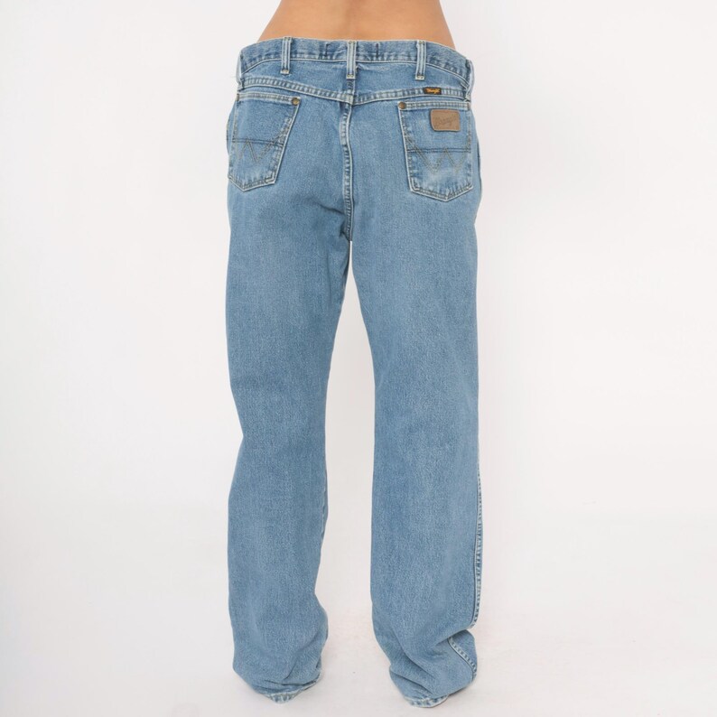 Peut inclure: Jean bleu clair avec une coupe classique &agrave; cinq poches. Le jean pr&eacute;sente une coupe droite et un patch en cuir marron sur la poche arri&egrave;re avec le nom de la marque. Le jean est en denim durable.