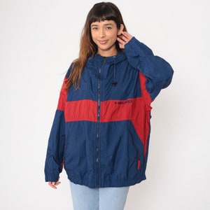 May include: A blue and red windbreaker jacket with a zipper closure and a hood. The jacket has the word "HEAD" printed on the front in white.