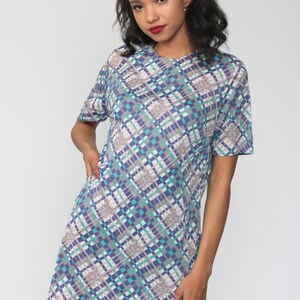 Puede incluir: Un vestido de manga corta con un patr&oacute;n geom&eacute;trico en tonos de azul, verde, blanco y gris. El vestido tiene un escote redondo y un ajuste holgado.