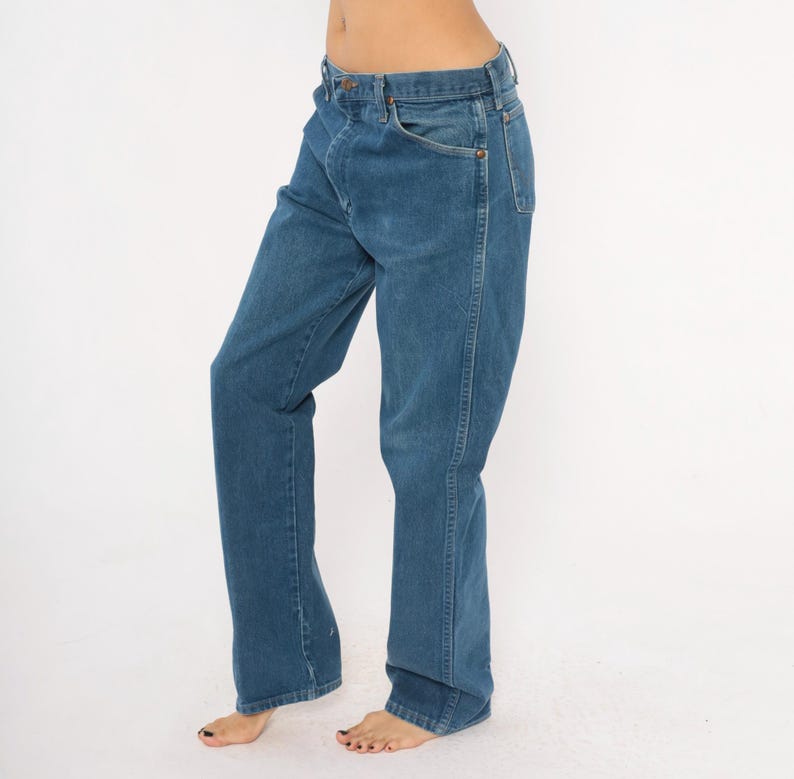 May include: Blue denim jeans with a classic five-pocket design. The jeans have a straight leg fit and a button and zipper closure. The denim has a medium wash with subtle fading and wear.