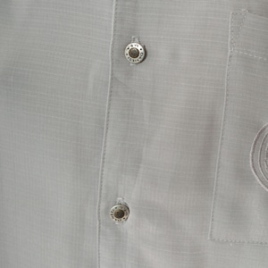 May include: Close-up of a gray button-down shirt with two silver buttons. The buttons have the text "Daniels U.S.A." engraved on them.