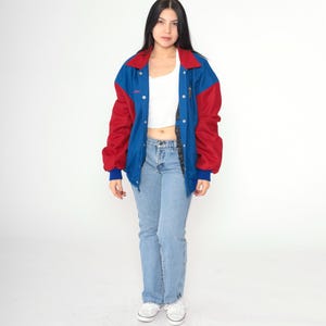 May include: A blue and red varsity jacket with a snap closure. The jacket has a white collar and a white stripe down the sleeves.