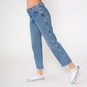 May include: A pair of light blue denim jeans with a straight leg fit. The jeans have a high waist and a frayed hem.