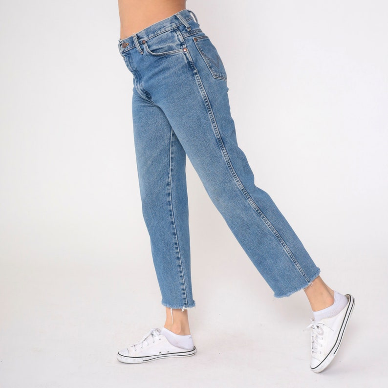 May include: A pair of light blue denim jeans with a straight leg fit. The jeans have a high waist and a frayed hem.