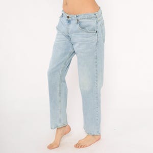 May include: Light blue denim jeans. The jeans have a classic five-pocket design, a button and zipper closure, and a straight leg fit. The jeans are a light wash, with subtle fading and wear.