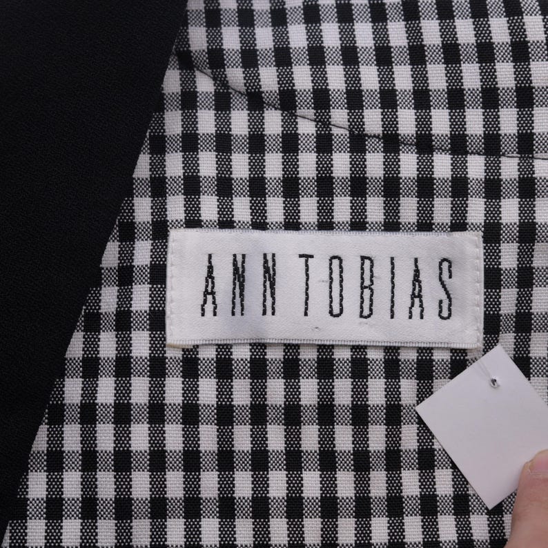 May include: A black and white gingham fabric with a white label that says "ANN TOBIAS" on it.