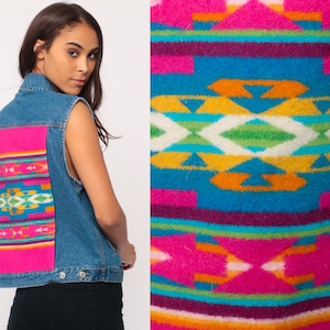 May include: A denim vest with a striking, patterned back. The panel displays a colourful geometric design in pink, blue, yellow, and green. The vest has a classic denim wash and button fastenings.